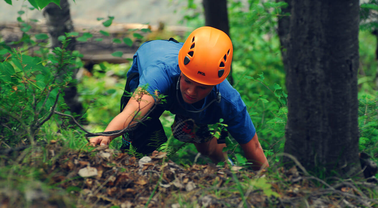 A camper climbing up the side of s steep forest hill